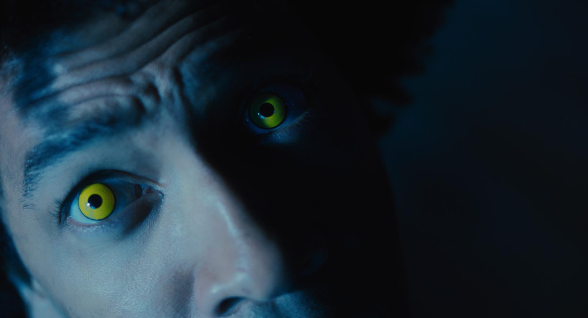 A man with yellow eyes looks up