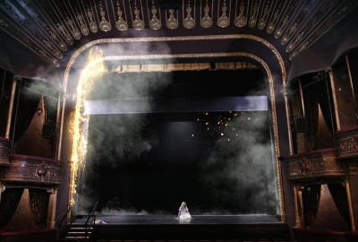 Someone sits on the stage of an old theater