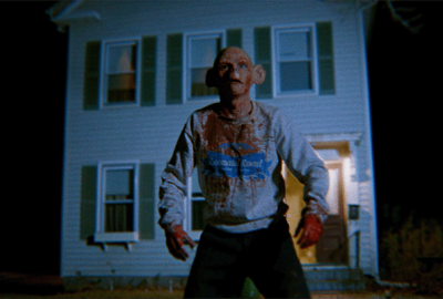 Ziggy the Humanzee covered in blood standing outside his home. 