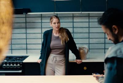 A woman speaks with a man in the kitchen