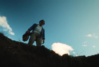 Man hold a human head above a large hole in the ground